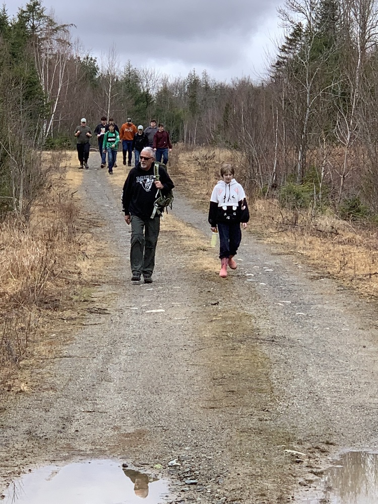 Teacher and students walking along a road in the woods. 